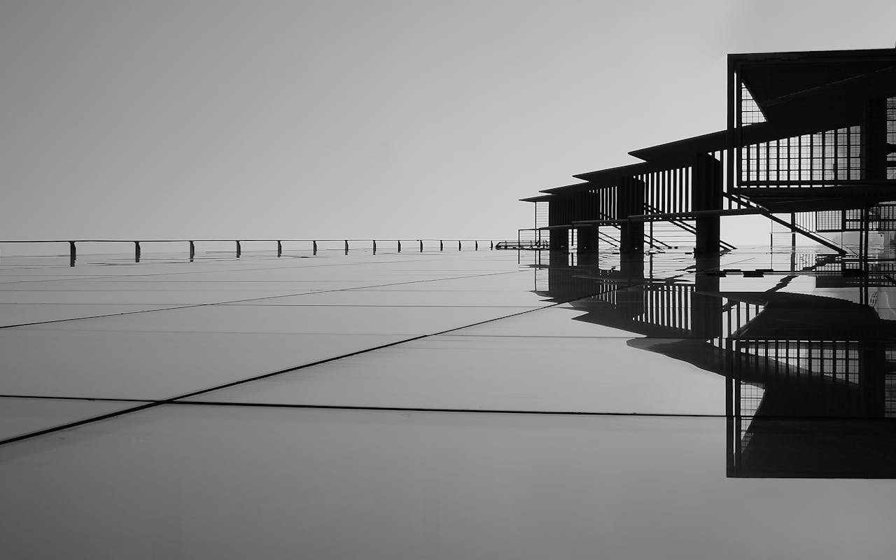who-we-are A striking minimalist black and white image featuring architectural reflections on glass surfaces.