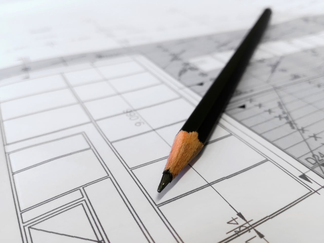 services-01 Detailed image of a black pencil resting on architectural blueprints, ideal for design and planning themes.